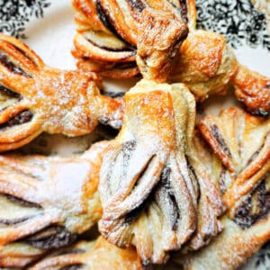 A plate with witches' brooms made with puff pastry and nutella and dusted with icing sugar.