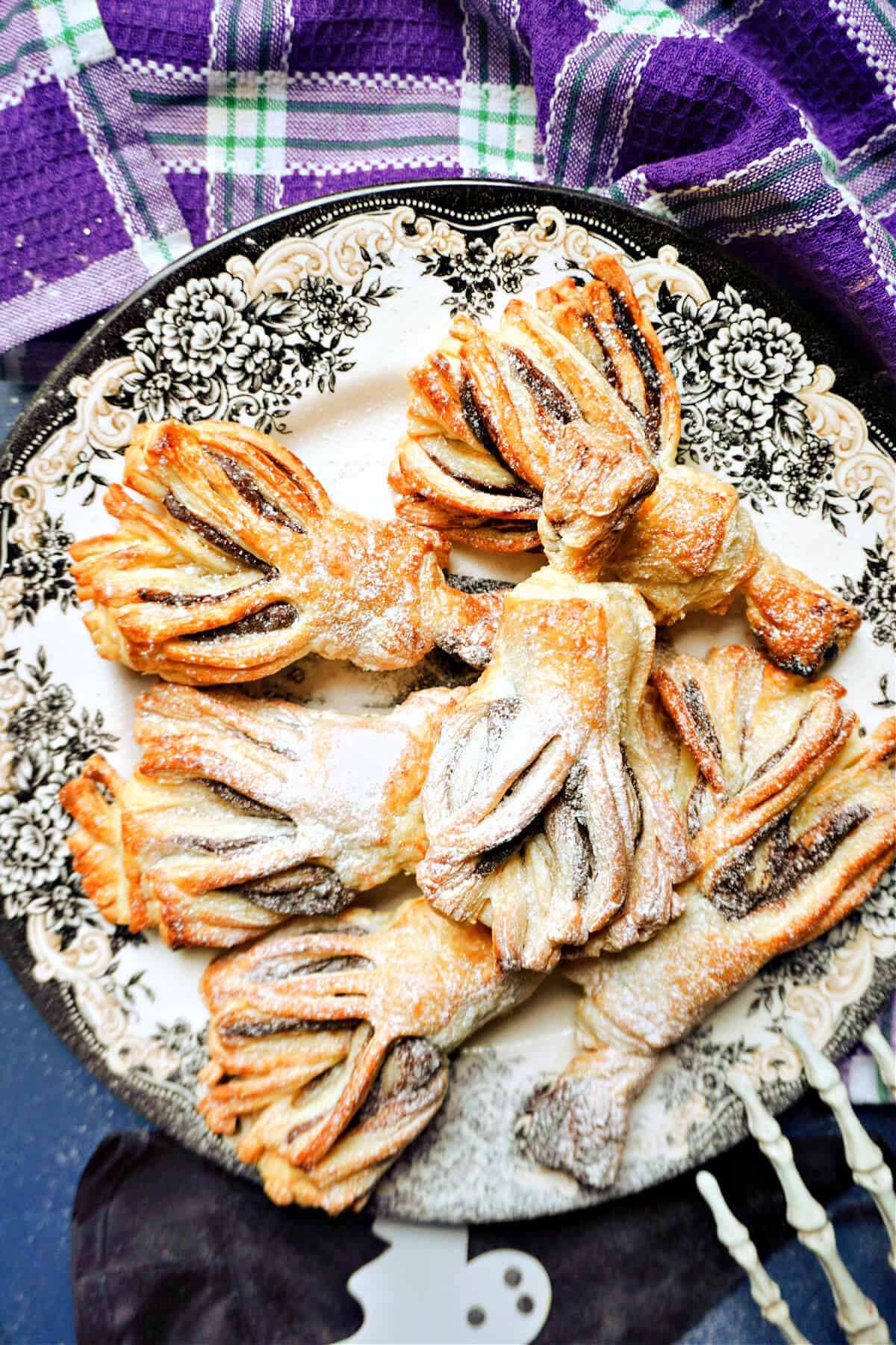 A Halloween-patterned plate with 6 puff pastry brooms.