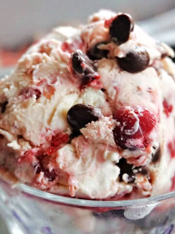 A dessert glass with cranberry ice cream topped with choc chips.