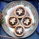 A festive plate with 4 mince pies topped with gingerbread men pastry.