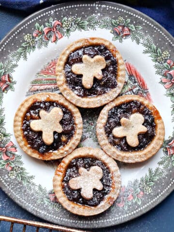 A festive plate with 4 mince pies topped with gingerbread men pastry.