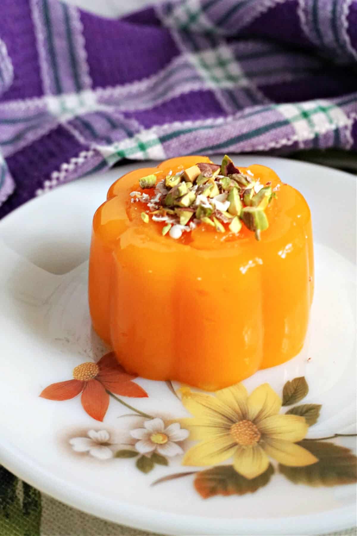A flowery plate with a mandarin jelly topped with chopped pistachios and grated chocolate.
