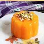 A flowery plate with a mandarin jelly topped with chopped pistachios and grated chocolate.