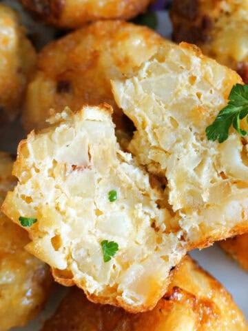 2 halves of a potato and egg muffin sitting on top of other whole muffins.