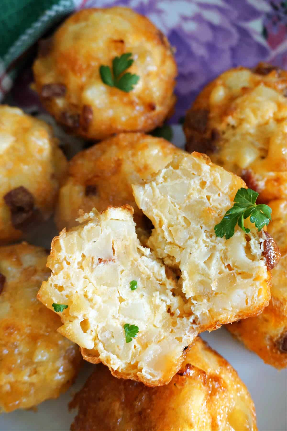 2 halves of a mini potato omelette sitting on top of other mini omelettes on a plate.