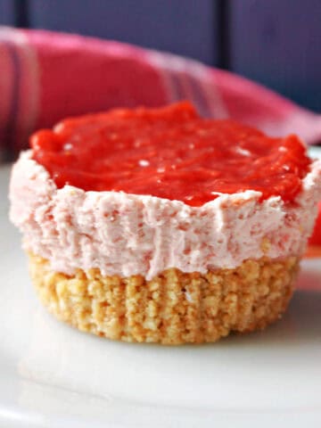 A white plate with a mini strawberry cheesecake and love hearts around.