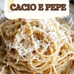 A white plate with a portion of spaghetti topped with grated cheese and black pepper.