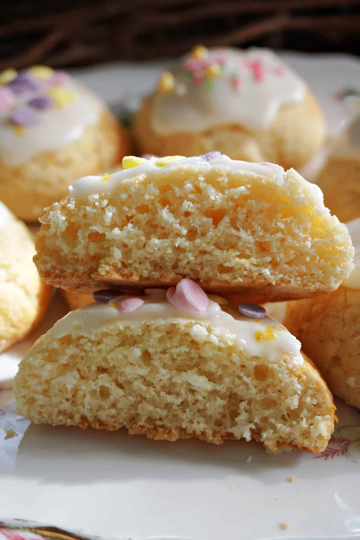 A stack with 2 halves of a lemon cookie with more cookies partially-visible in the background.