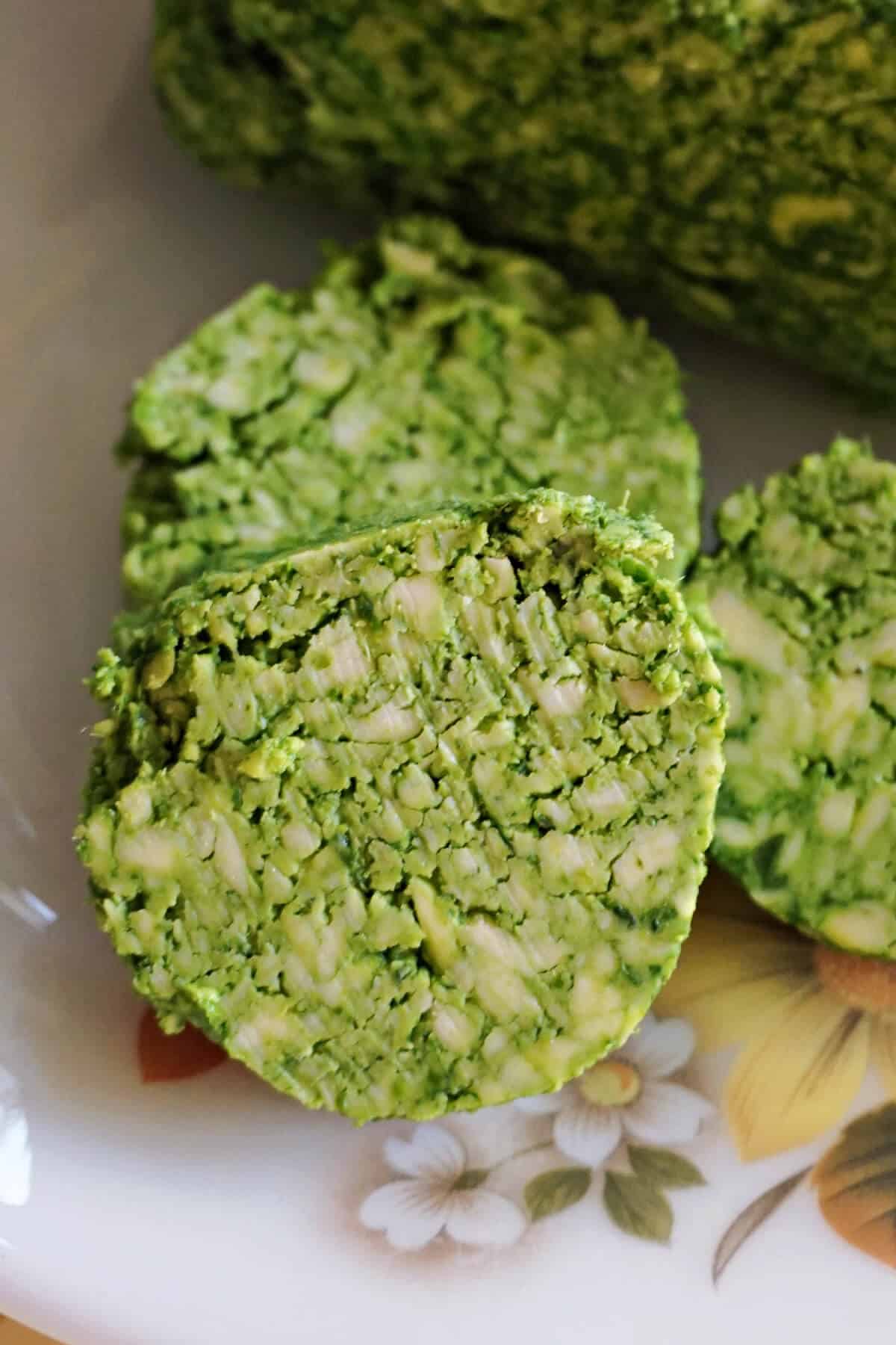 Close-up of 3 slices of wild garlic butter on a wooden board.