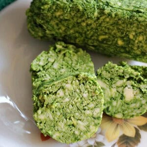 A white plate with 3 slices of wild garlic butter next to a long of wild garlic butter.