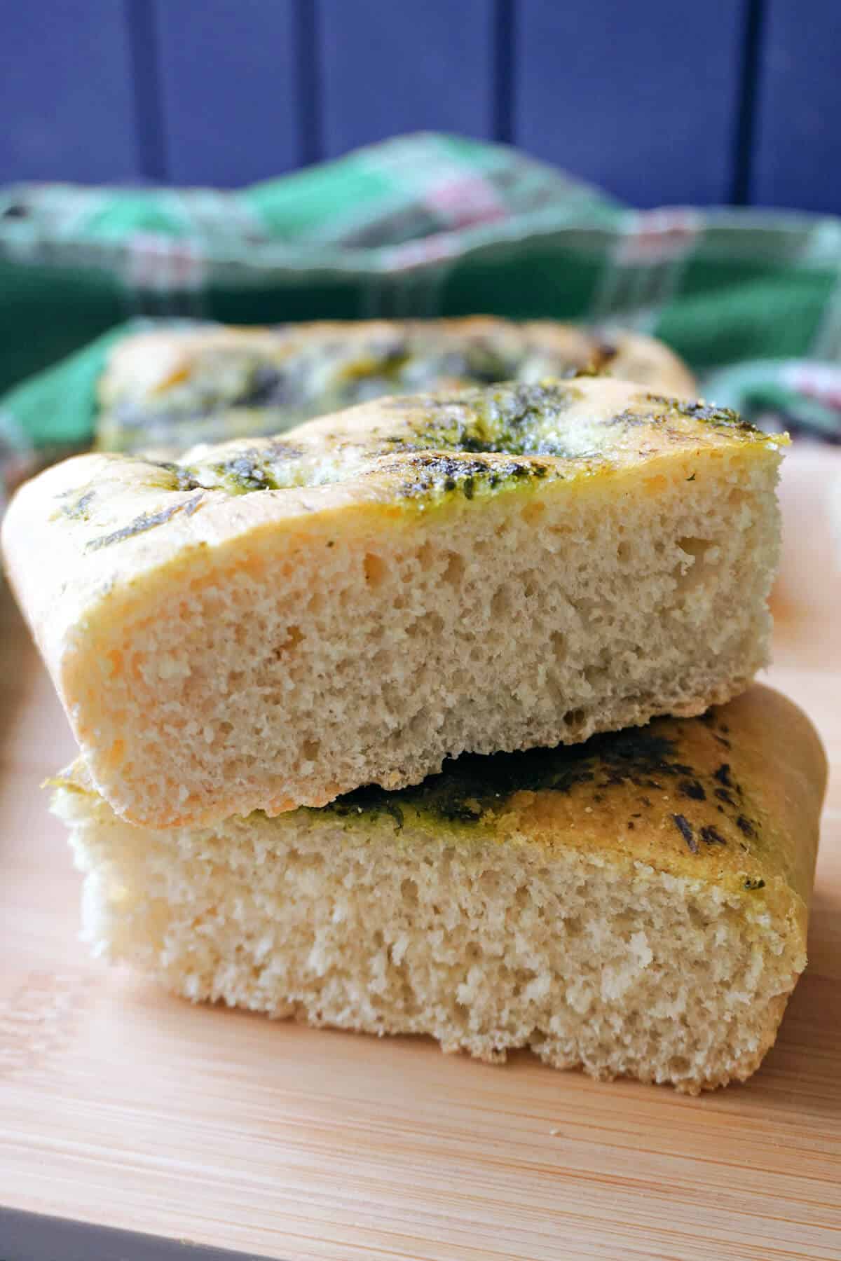 A stack of 2 slices of focaccia on a wooden board.