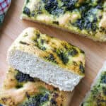 A wooden board with slices of focaccia topped with wild garlic.