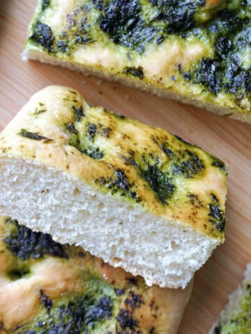A wooden board with slices of focaccia topped with wild garlic.