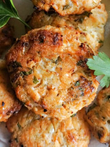 Salmon patties garnished with fresh parsley leaves.
