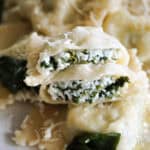 2 halves of a ravioli sitting on top of other whole ravioli.