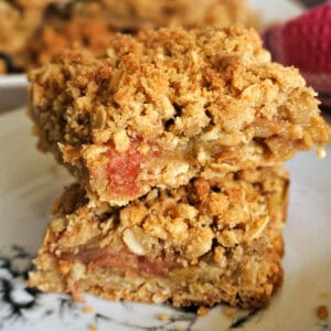 2 slices of rhubarb crumble bars piled up on a white plate.