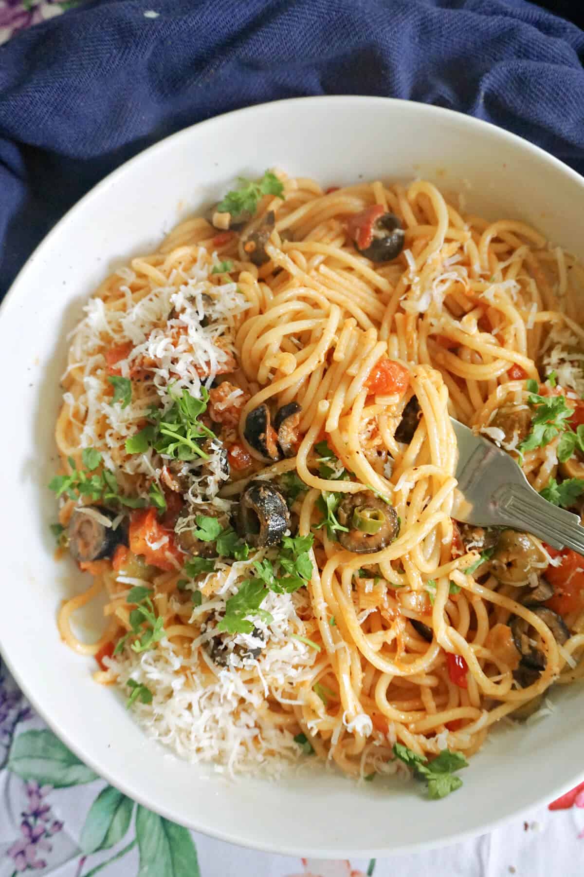 A white bowl with a portion of spaghetti puttanesca.