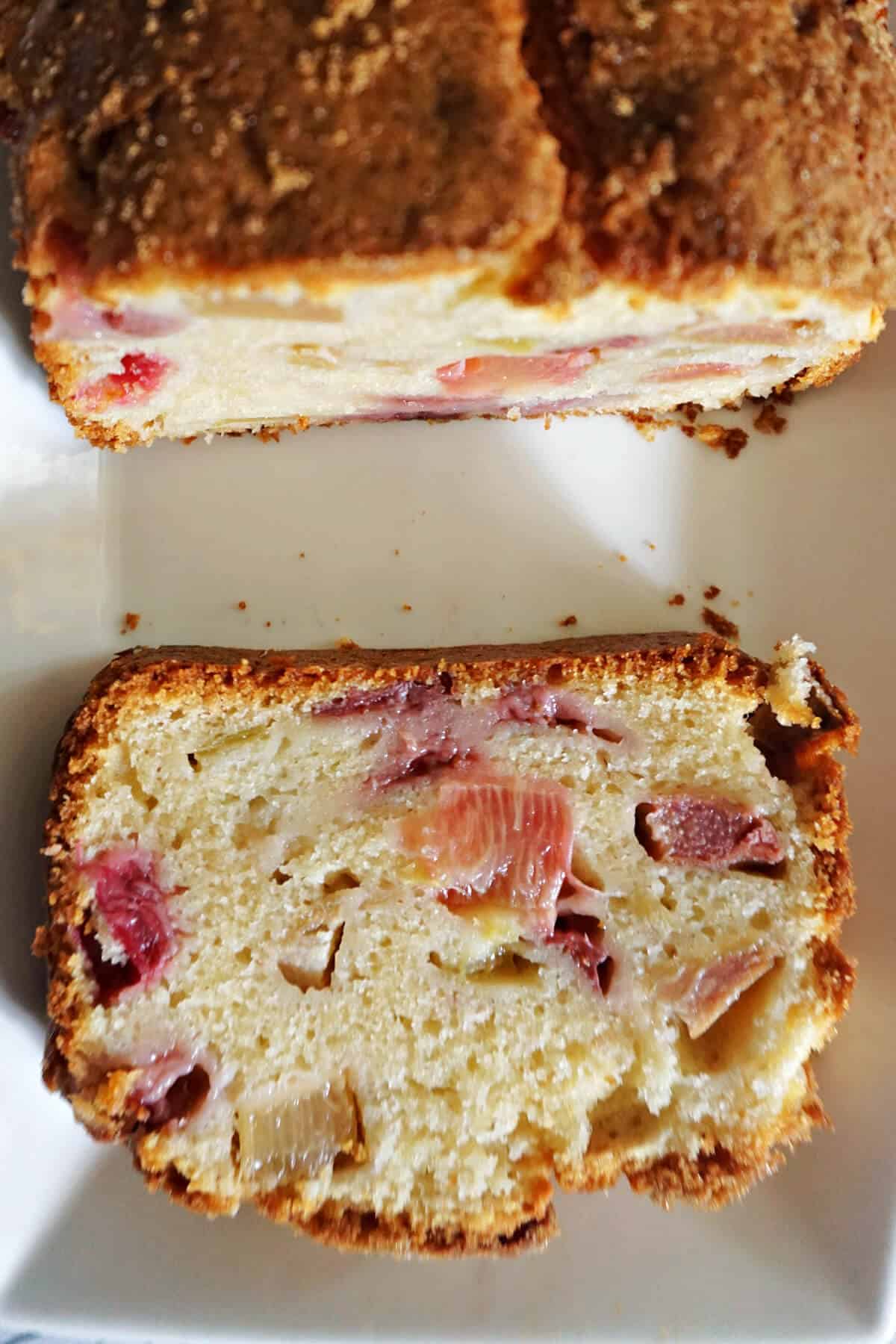 A white rectangle plate with a slice of fruit cake and a sliced loaf cake.