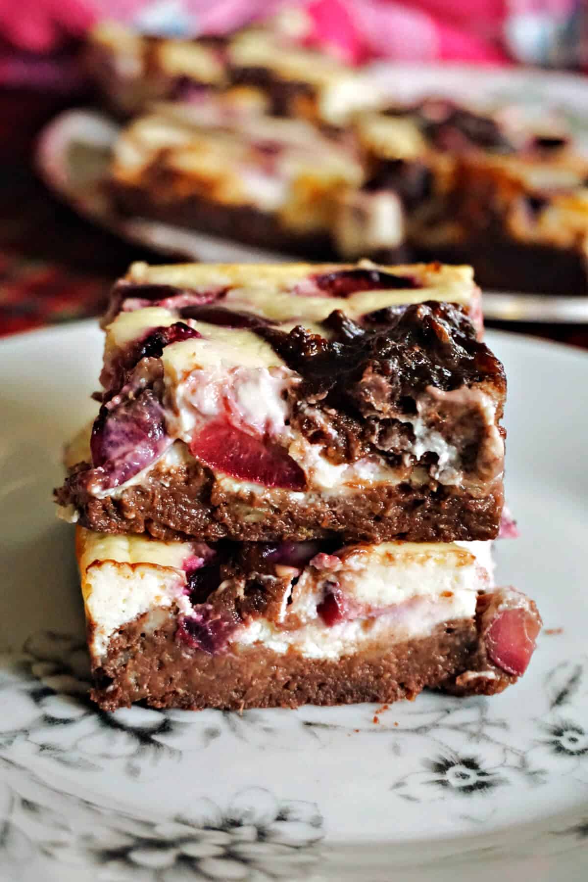 A stack of 2 brownies on a white plate.