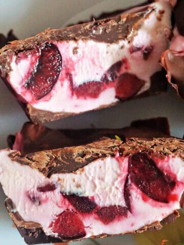 2 halves of a chocolate-covered cherry cheesecake cup on a white plate.