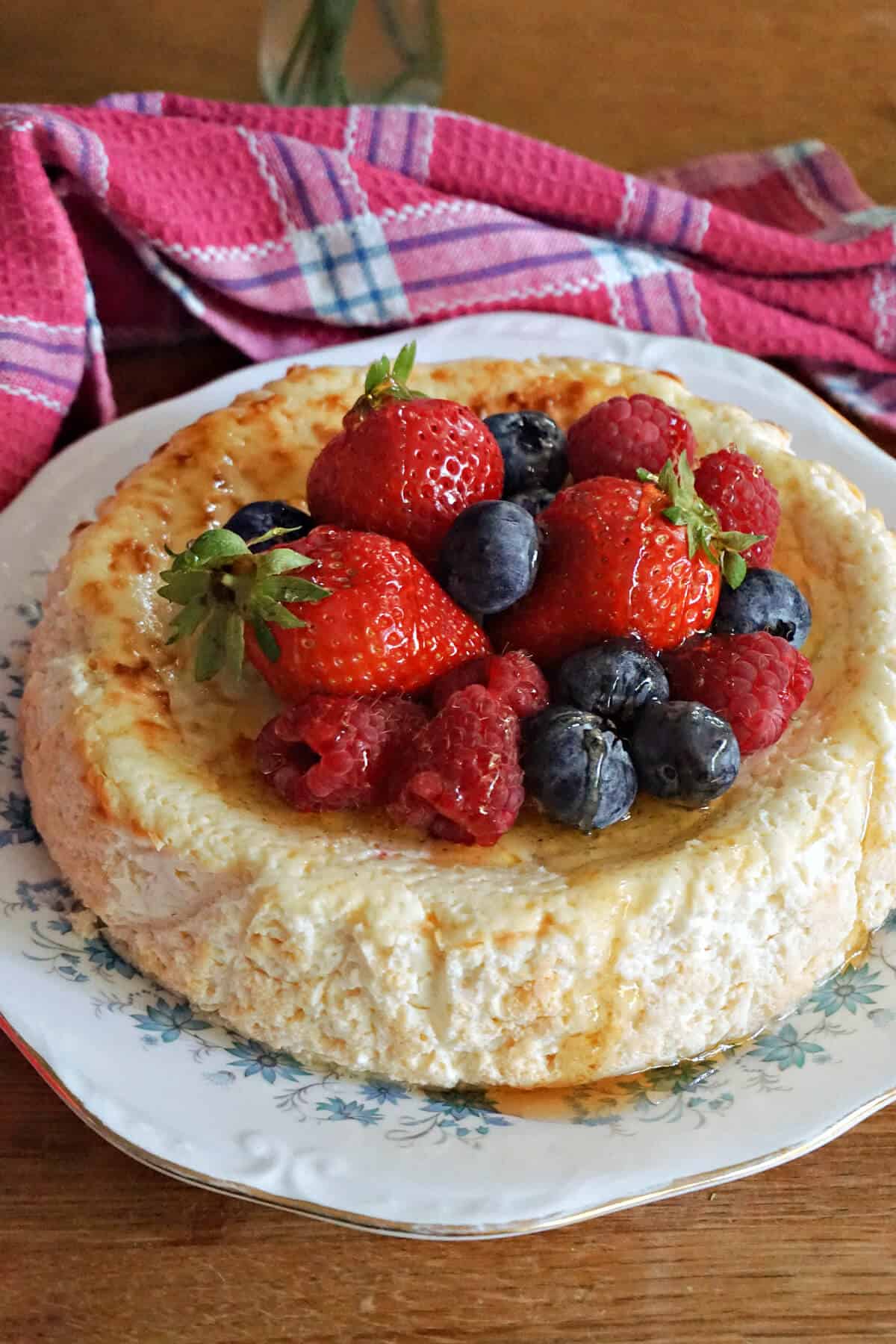 A plate with a cheesecake topped with berries and honey.