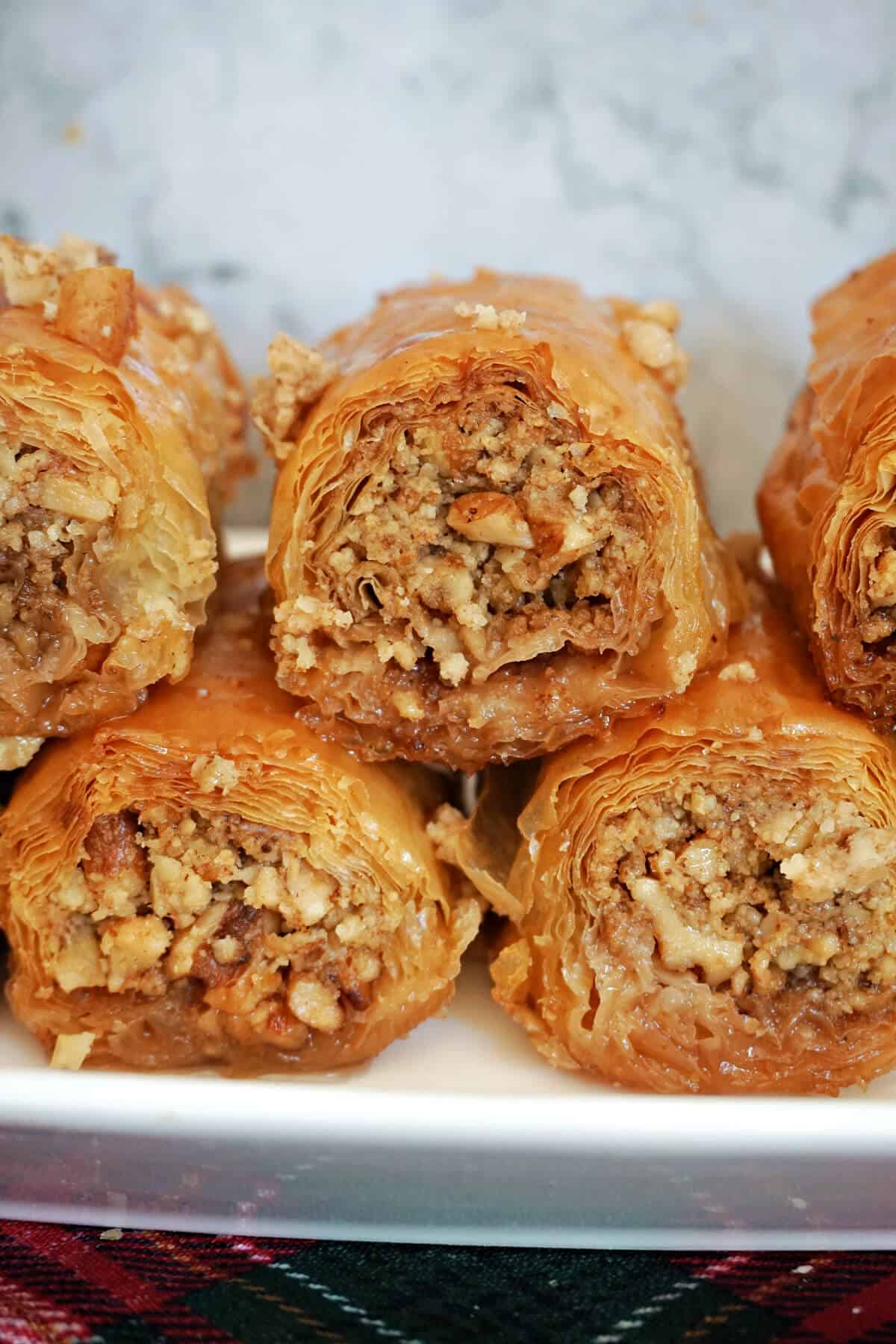 A white plate with 6 baklava rolls, some partially visible.