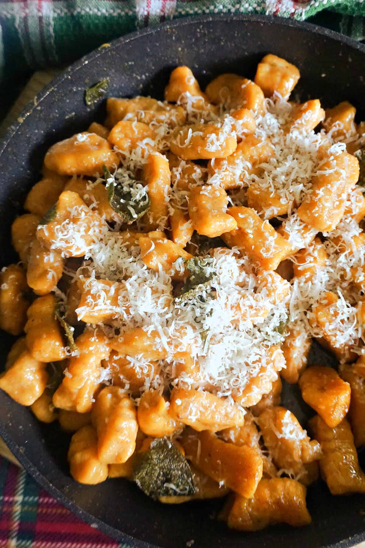 A pan with sweet potato gnocchi topped with grated parmesan.