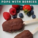 A white plate with 2 chocolate-covered popsicles and fresh berries around.