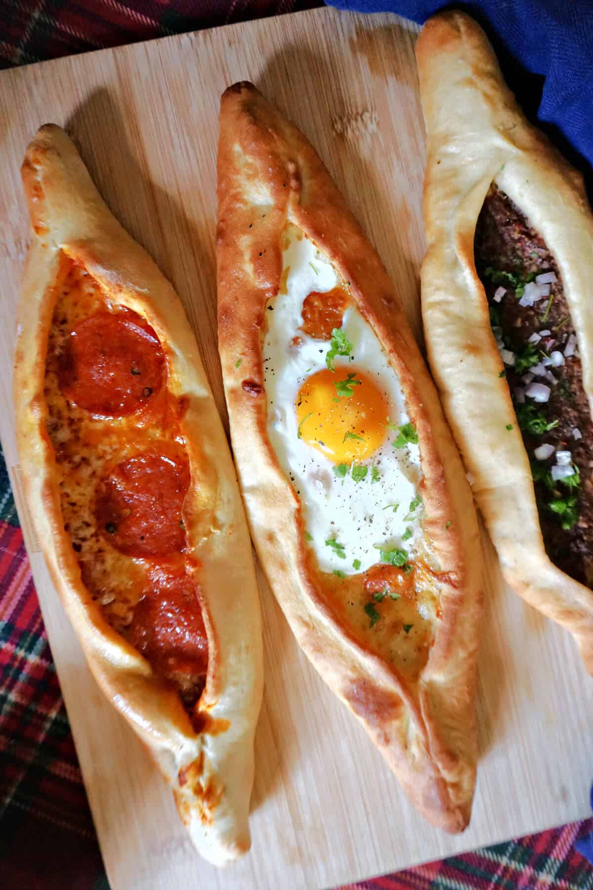 3 Turkish pide on a wooden board.