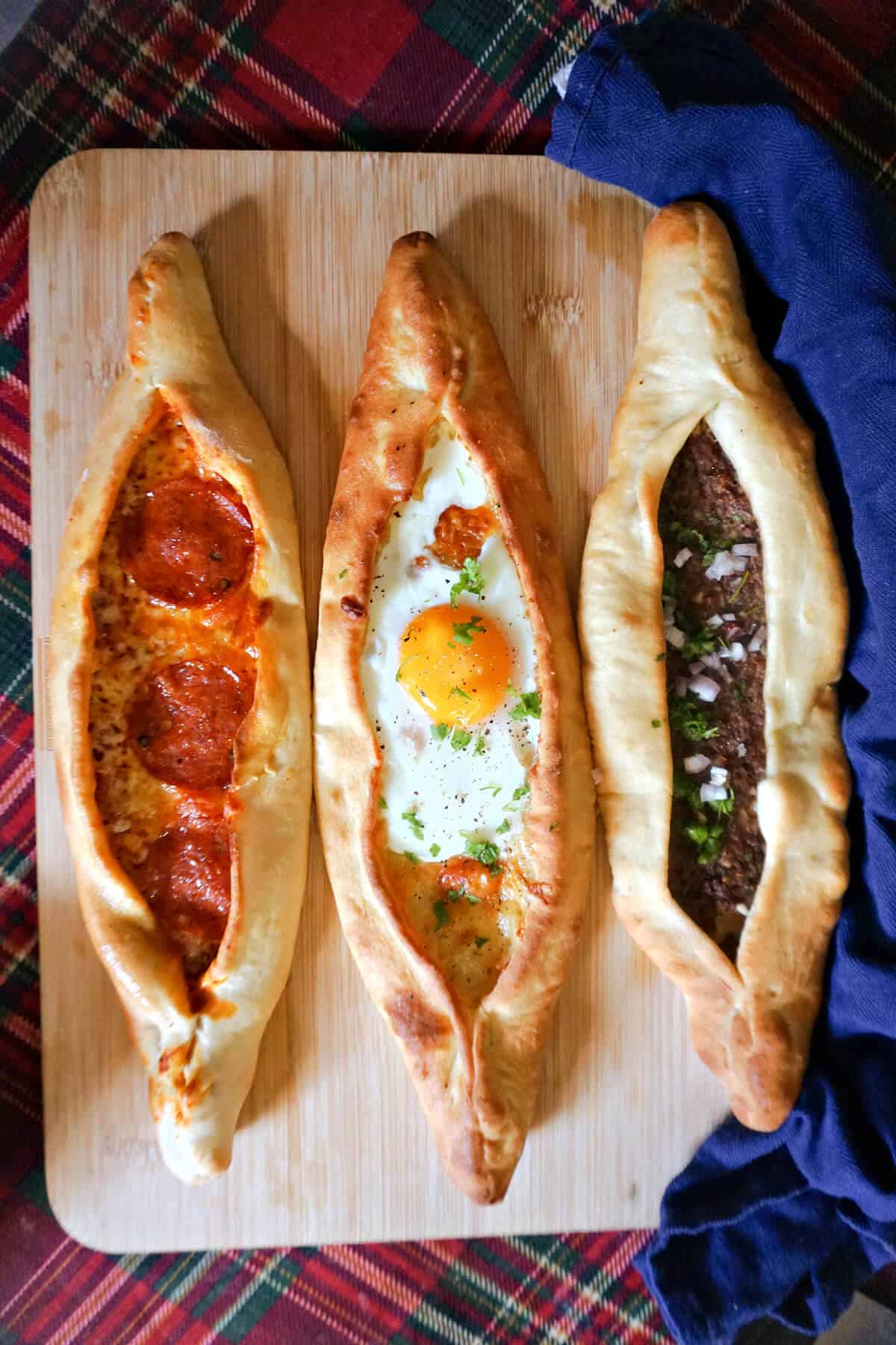 3 Turkish Pide on a wooden board.