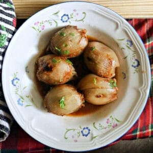 A white flowery plate with stuffed onions in broth.