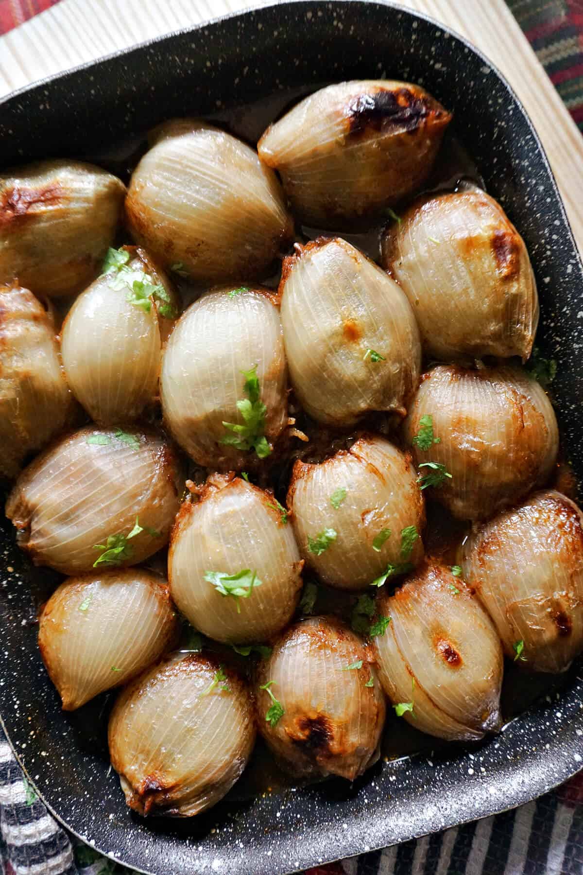 A baking tray with stuffed onions in a tomato sauce.