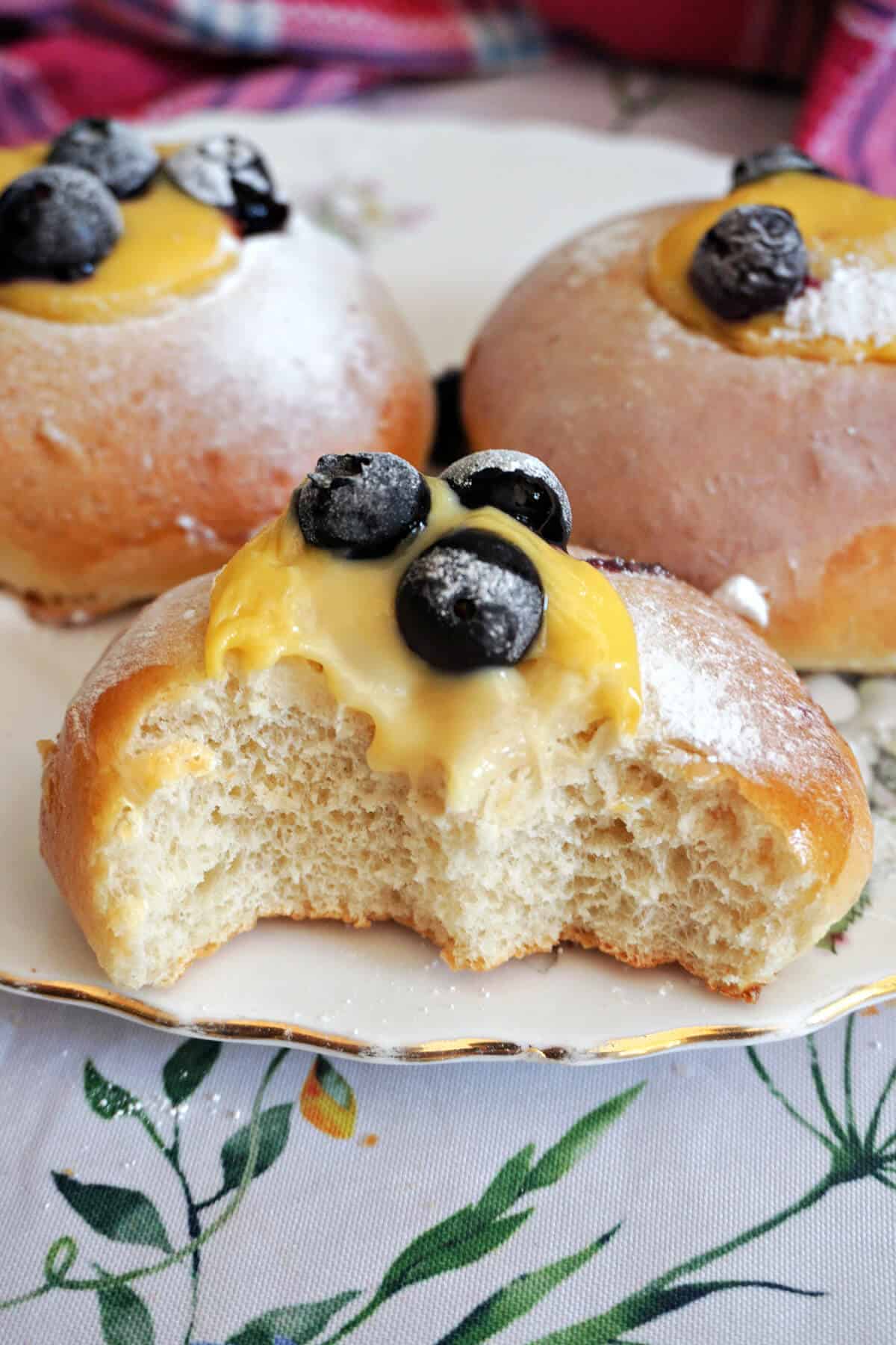 Half-bitten custard bun with 2 whole buns in the background.