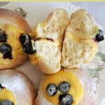 A white plate with 2 halves of a custard bun and 3 partially-visible whole buns.