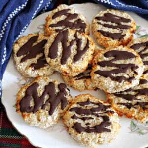 A white plate with chocolate-dipped cookies and a blue tea towel around it.