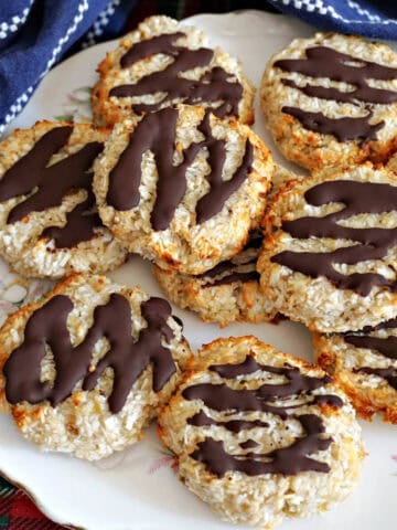 A white plate with chocolate-dipped cookies and a blue tea towel around it.