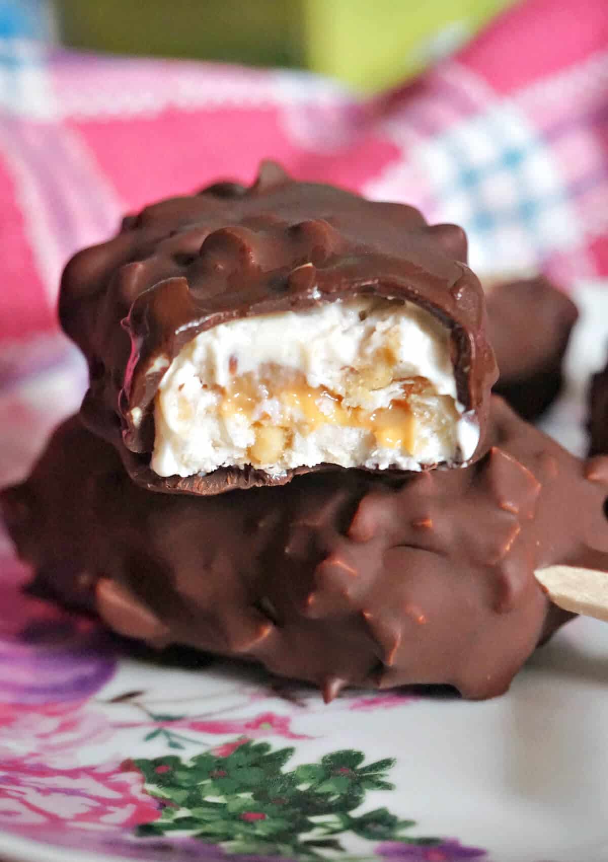 A stack of 2 halves of a chocolate-covered frozen yogurt bar.