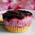A small blackberry cheesecake on a white plate.