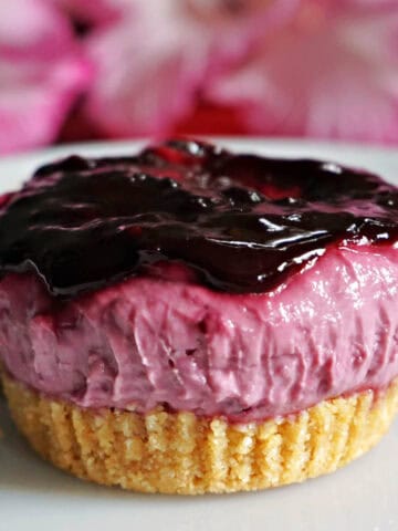 A small blackberry cheesecake on a white plate.