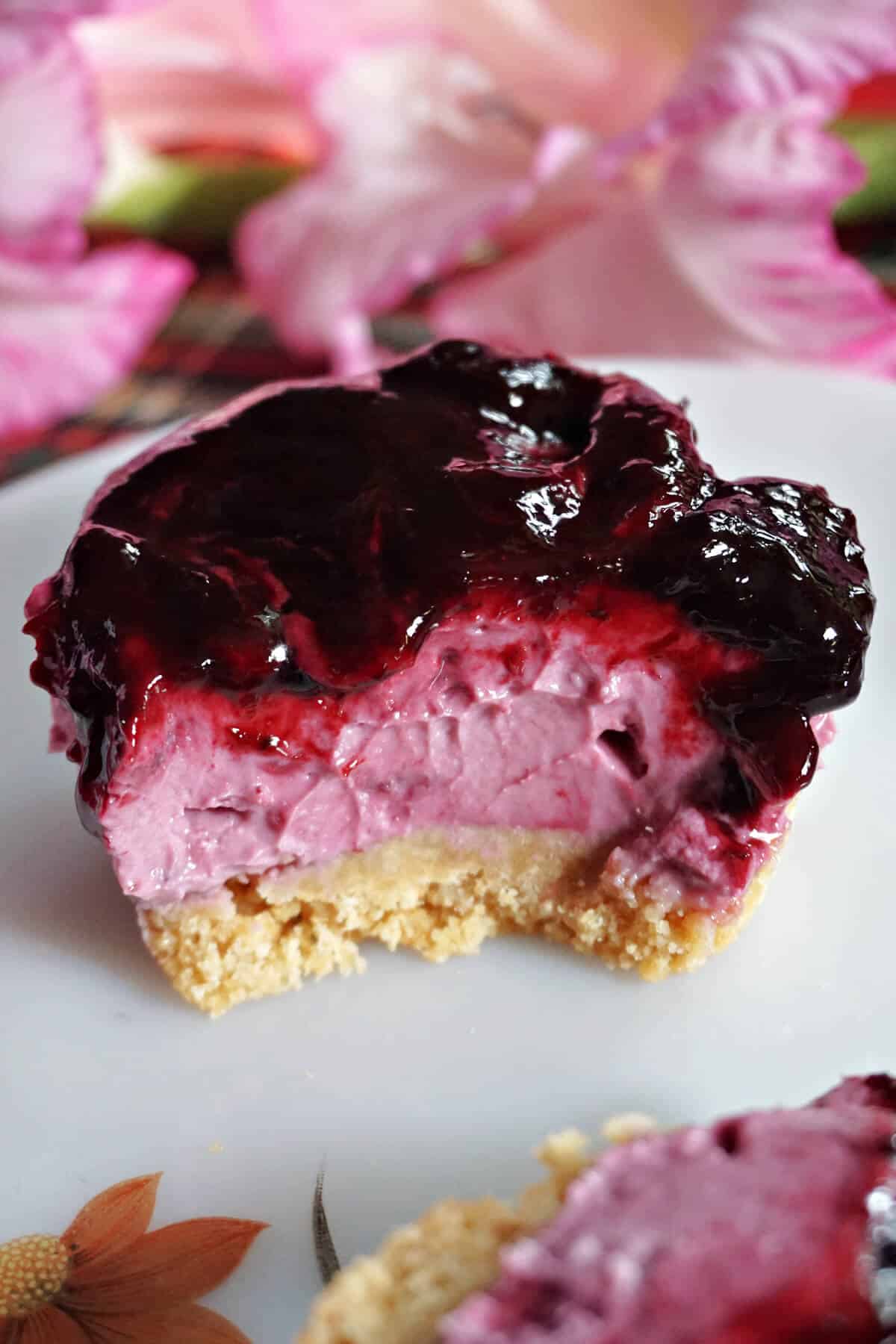 Half a mini blackberry cheesecake on a white plate.