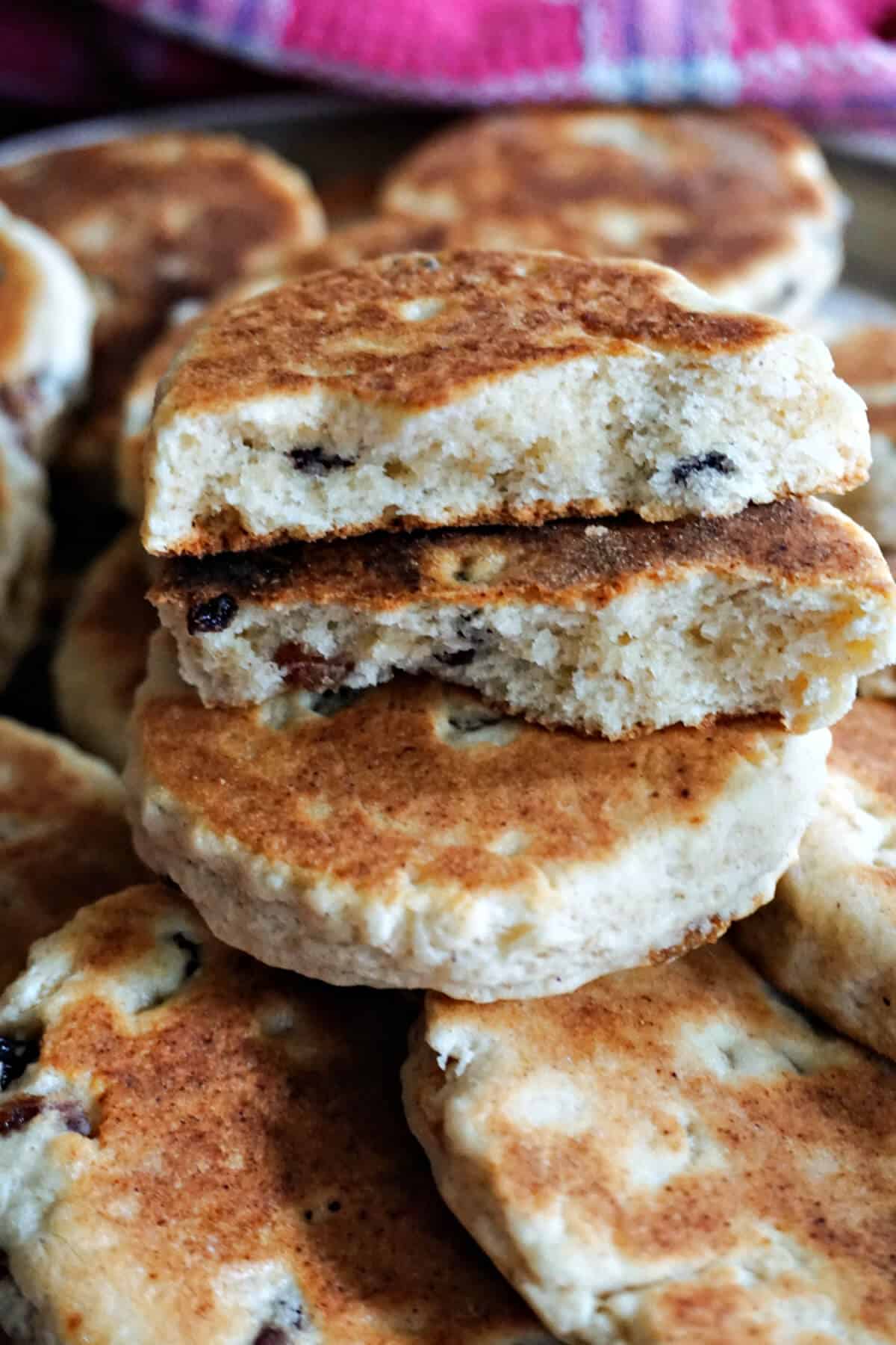 2 halves of a Welsh cake sitting on top of other whole cakes.