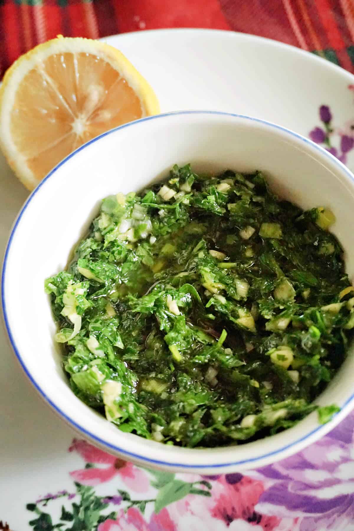 A white ramekin with parsley sauce.