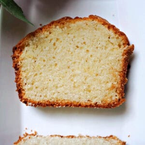 A white plate with a slice of sponge cake and another partially-visible slice.
