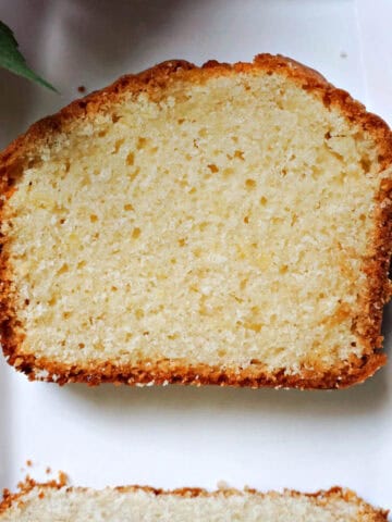 A white plate with a slice of sponge cake and another partially-visible slice.
