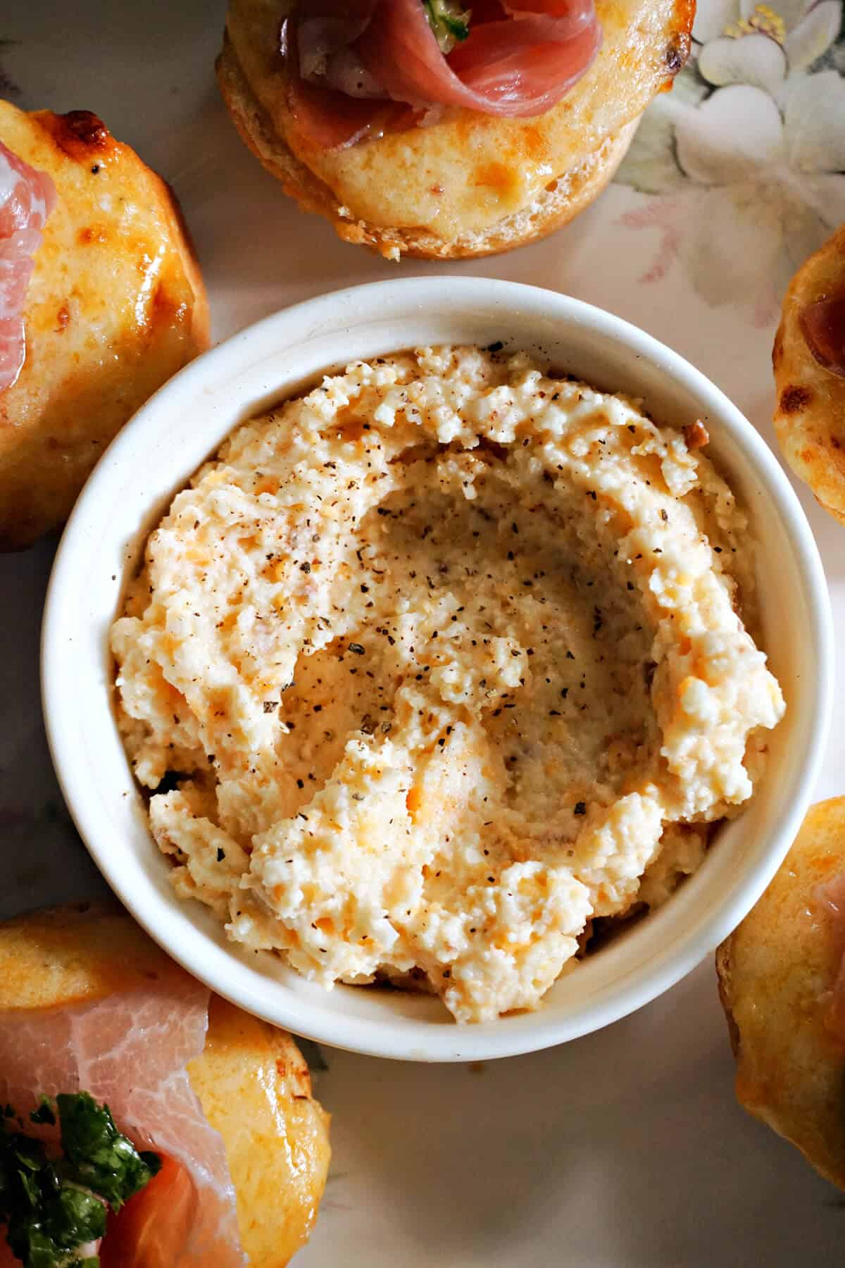 A white ramekin with cheese spread and air fried baguettes.