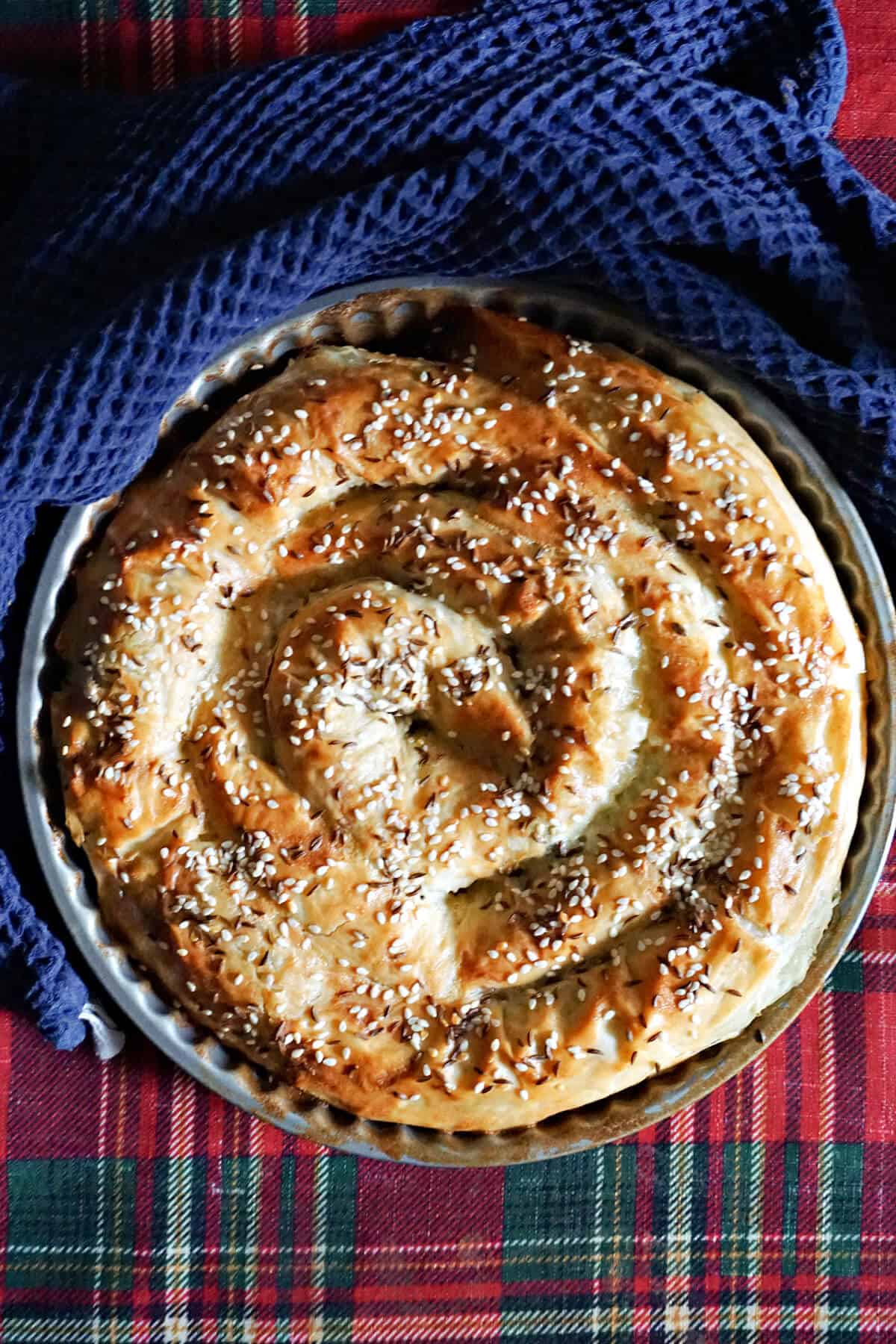 A dish with spiral borek and a navy blue kitchen towel around.