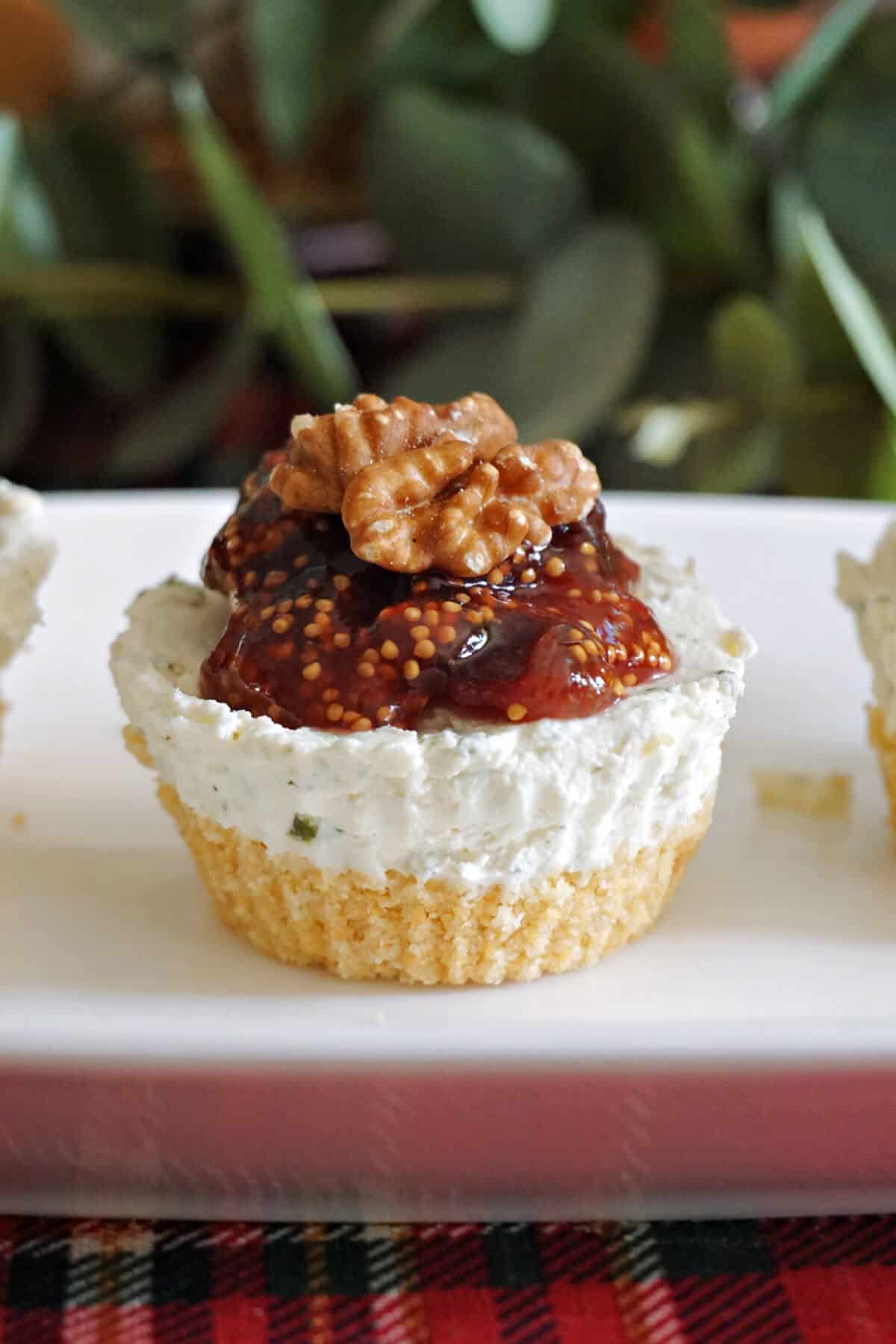A mini cheesecake topped with fig jam and a walnut half.