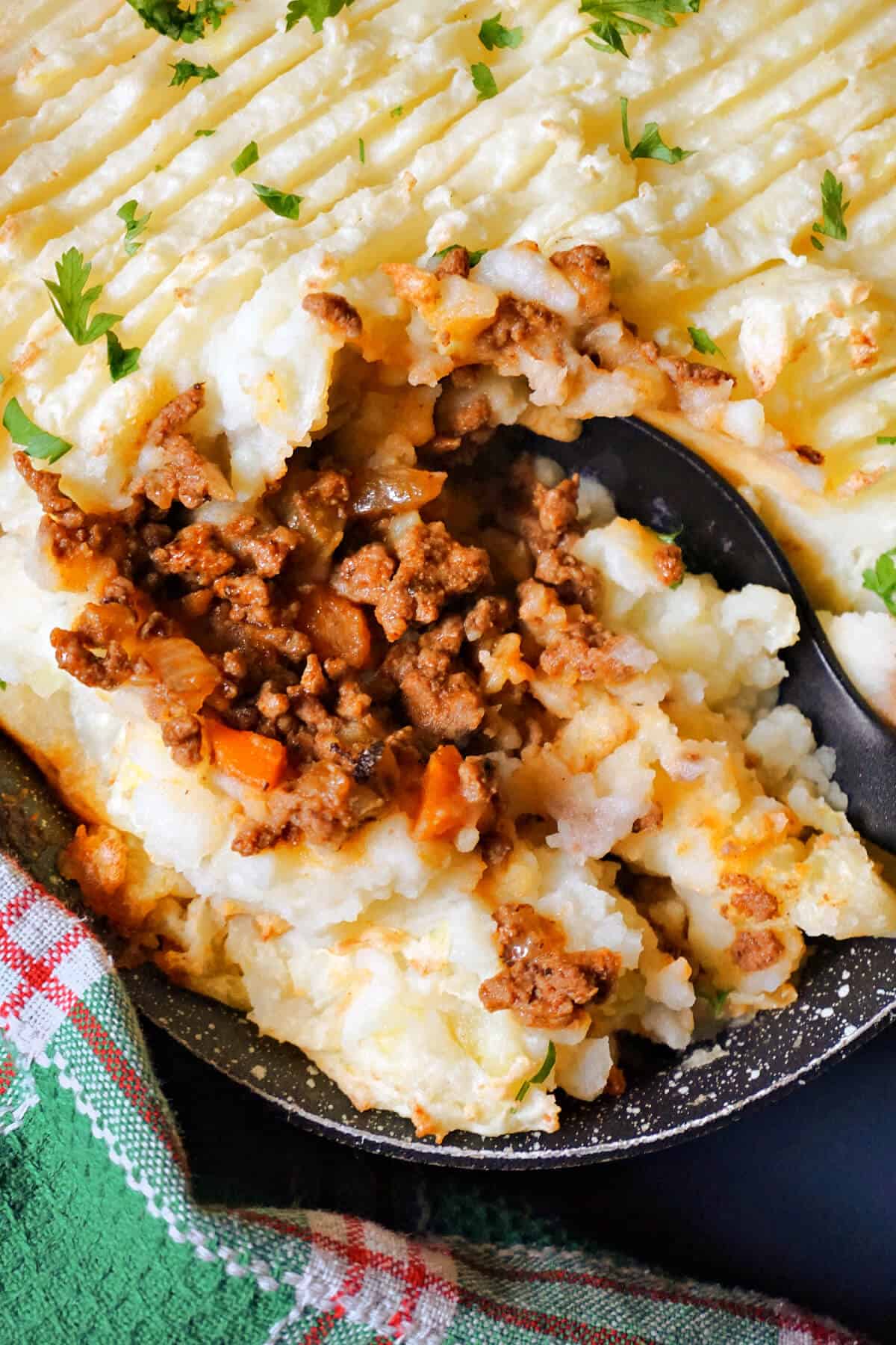 A dish of cottage pie with a spoon.