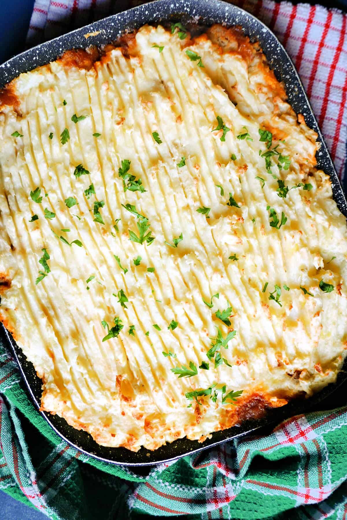 A dish with cottage pie stopped with chopped parsley.